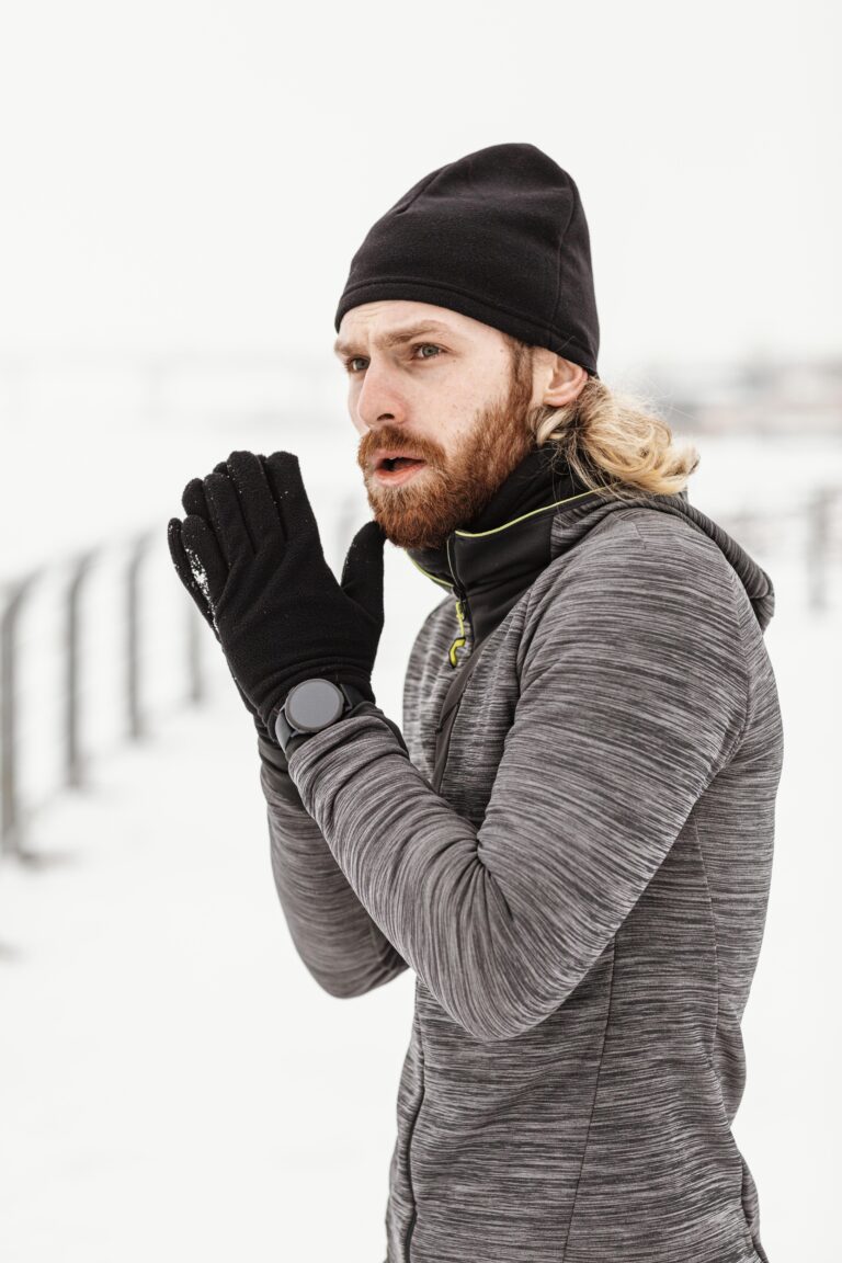 A person standing outside in cold weather, wearing hand warmer gloves, their hands cupped together to stay warm.